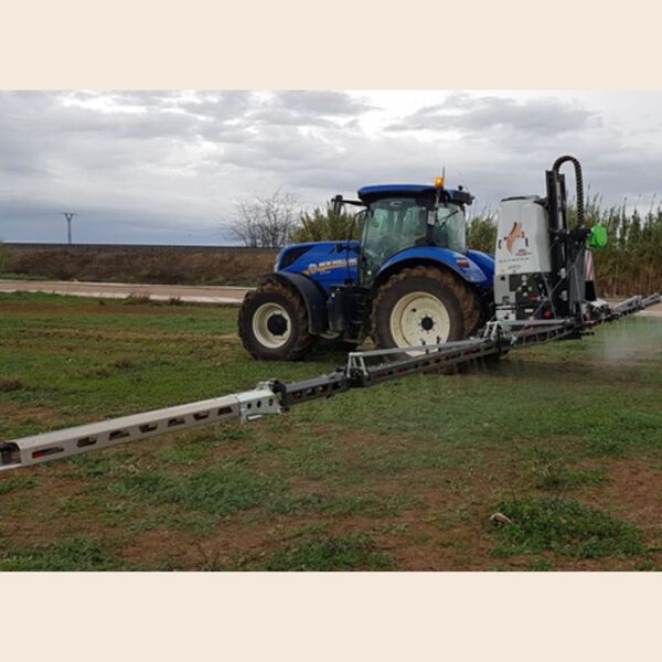 Tractor agrícola azul New Holland con pulverizador de barras extendidas aplicando fitosanitarios en un campo, bajo un cielo nublado, simbolizando una aplicación cualificada.